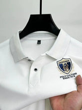 Zoomed in front view of white Equestrian Crest Designer Polo on hanger.