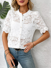 Model wearing a white lace button-down shirt with faux pearl buttons, styled with light denim jeans and gold hoop earrings having coffee at a cafe.