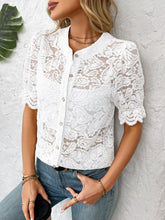 Side profile of model in a white lace shirt with wavy ruffle sleeves, styled with sleek hair, statement earrings, and tailored pants.