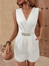 Model standing in white romper with gold accessories.