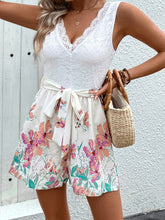 Model showcasing Serenique Petal Playsuit with white lace V-neck top, floral-patterned bottom, and tie waist, perfect for stylish summer occasions.