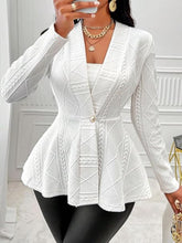 A woman taking a selfie photo at a restaurant wearing the white One Button Textured Peplum Cardigan paired with black leather pants, jewelry, and heels.