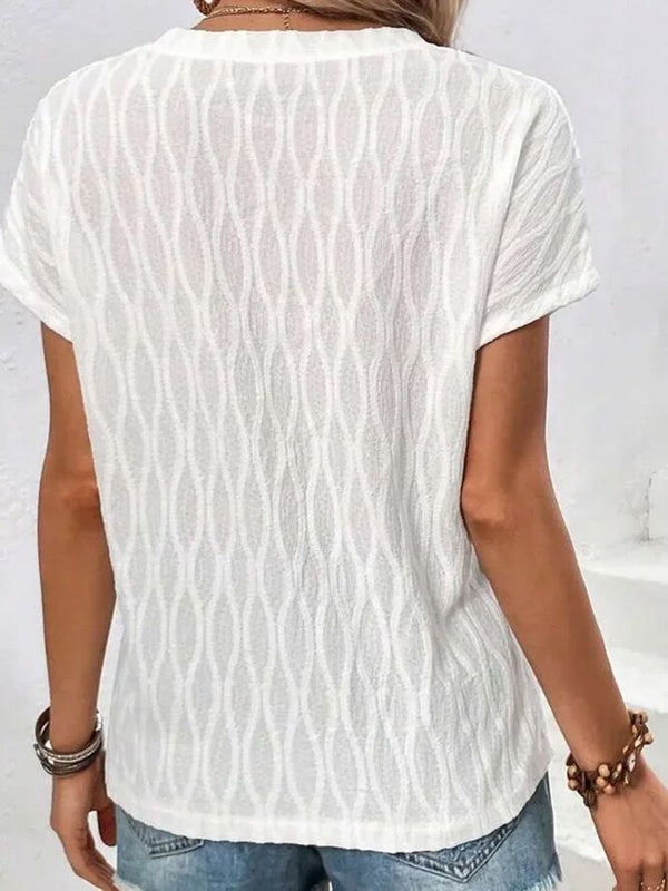 A woman showcasing the back of a white Full Size Ruched Wavy Textured Round Neck Short Sleeve T-Shirt riding the subway in New York City.
