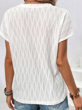 A woman showcasing the back of a white Full Size Ruched Wavy Textured Round Neck Short Sleeve T-Shirt riding the subway in New York City.