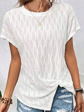 A woman walking on the beach wearing the white Ruched Wavy Pattern Round Neck Short Sleeve T-Shirt paired with distressed denim shorts, jewelry, and sandals.