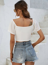 Back view of Glowflutter Crop Top showing soft fabric and flutter sleeve flow, worn by model in white.