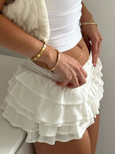 Model styling White Rivéla Ruche Skirt with crop top, purse, and gold accessories