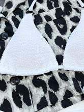 Close-up zoomed in  front view of white textured halter neck tie side bikini set with gold O-ring connectors bikini top, highlighting premium texture