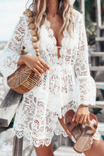 Close-up front view of white V-neck lace cover-up dress showing floral design, ruffle sleeves, and wavy hem