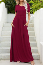 Model posing on a white staircase wearing the wine red Blissurella Maxi Tee Dress with gold jewelry and tan heels for an intimate dinner date.
