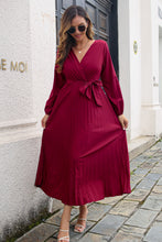 Model in Wine Zeleviane Pleated Maxi Dress featuring surplice neckline, pleated skirt, and tied waist detail.