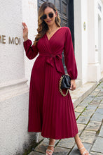 Side profile of Wine Zeleviane Pleated Maxi Dress, capturing graceful pleat movement and curve-enhancing wrap fit.