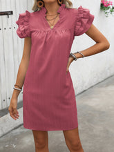 Feminine in dusty pink Calivémuse™ dress with one hand on her hip standing urban street side.
