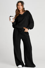 Woman holding a takeaway coffee while walking from a café, dressed in casual-chic MotoLux Vesper set in black.