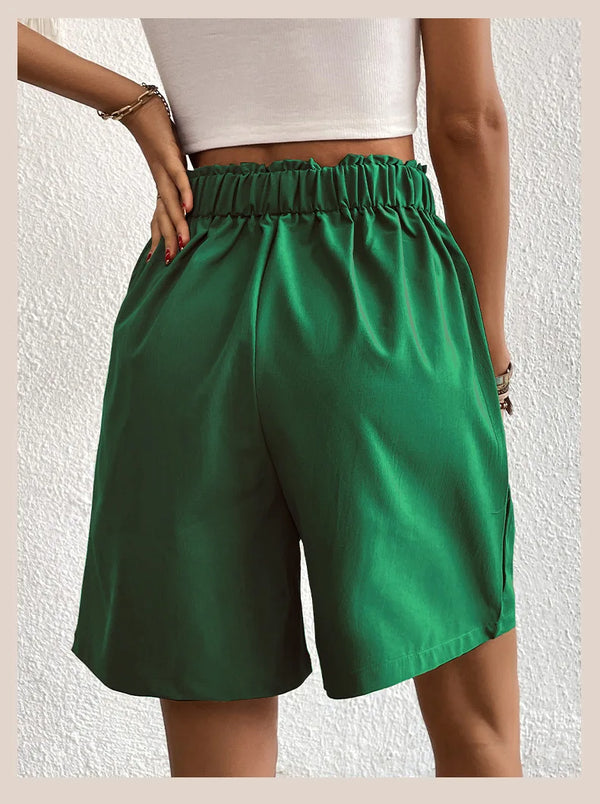 Women's dark green partial elastic high waist pleated baggy trouser shorts, back view.