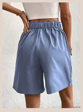 Women's light blue partial elastic high waist pleated baggy trouser shorts, back view.