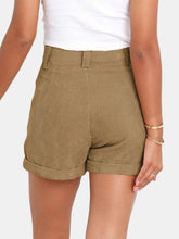 Female showcasing the back side of a pair of Camel Metropolitan Maven High-Waist Shorts paired with a white tank top and jewelry.
