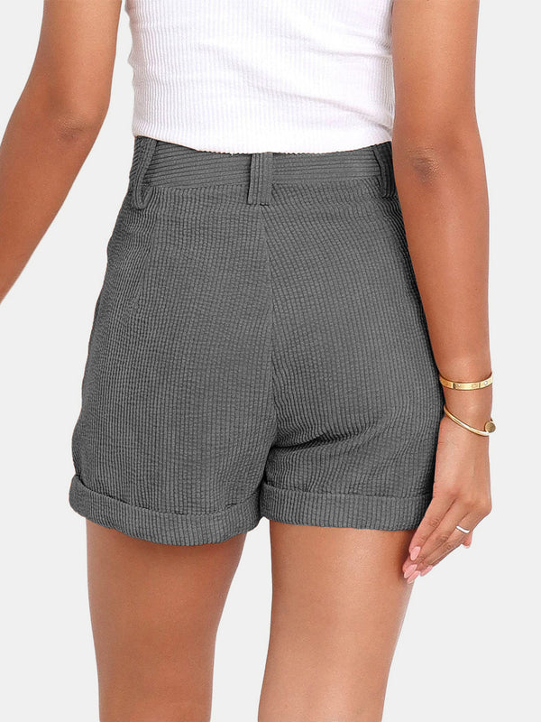 Woman showcasing the back side of a pair of dark gray Metropolitan Maven High-Waist Shorts paired with a white tank top and jewelry.