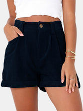 Woman modeling the dark navy Metropolitan Maven High-Waist Shorts paired with a white tank top and jewelry.
