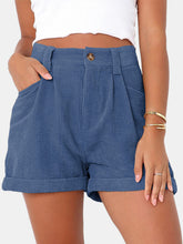 Woman modeling the Dusty Blue Metropolitan Maven High-Waist Shorts paired with a white tank top and jewelry.