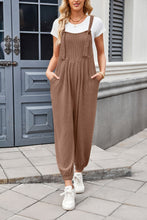 Side view of model in brown Xévia Overalls showing pocket detail and elasticated ankle cuffs.