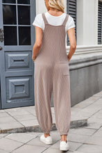 Back view of model in camel Xévia Overalls featuring knotted straps, a single back pocket, and ribbed texture.