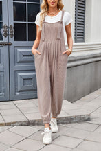 Model styling camel Xévia Overalls with a casual tank, gold bangles, and white sneakers for a sunny daytime look.