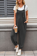 Dark gray Xévia Overalls with adjustable knotted straps, front view.
