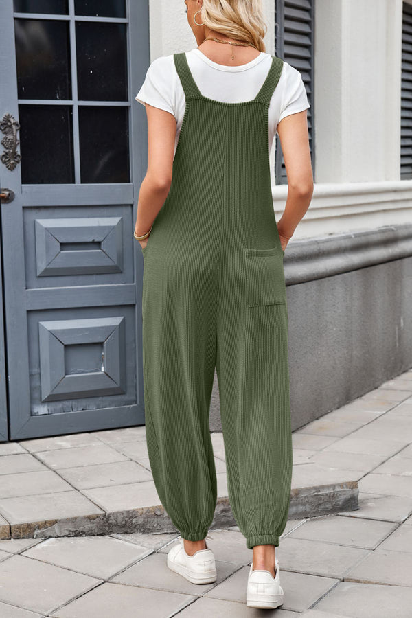 Model showcasing the back view of dark green Xévia Overalls with knotted straps, a single back pocket, and gathered ankle cuffs.
