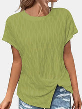 A woman walking on the beach wearing the yellow-green Ruched Wavy Pattern Round Neck Short Sleeve T-Shirt paired with distressed denim shorts, jewelry, and sandals.