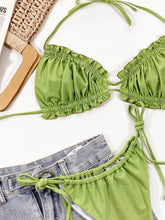 Close-up flat lay detail of yellow-green frill trim halter neck bikini set showing adjustable tie strings and frill trim detail