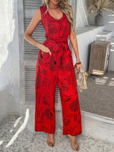 Model accessorized with black heels and clutch, wearing scarlet Zauraphina jumpsuit.