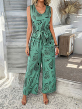 Model wearing turquoise Zauraphina jumpsuit with elegant all-over print, standing near a coastal backdrop.