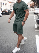 Front walking view of men’s army green Zavren EaseForm Set with cuffed sleeves and stitched shorts.
