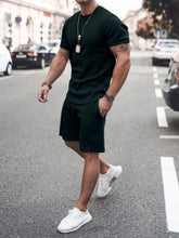 Front walking view of men’s black Zavren EaseForm Set with cuffed sleeves and stitched shorts.