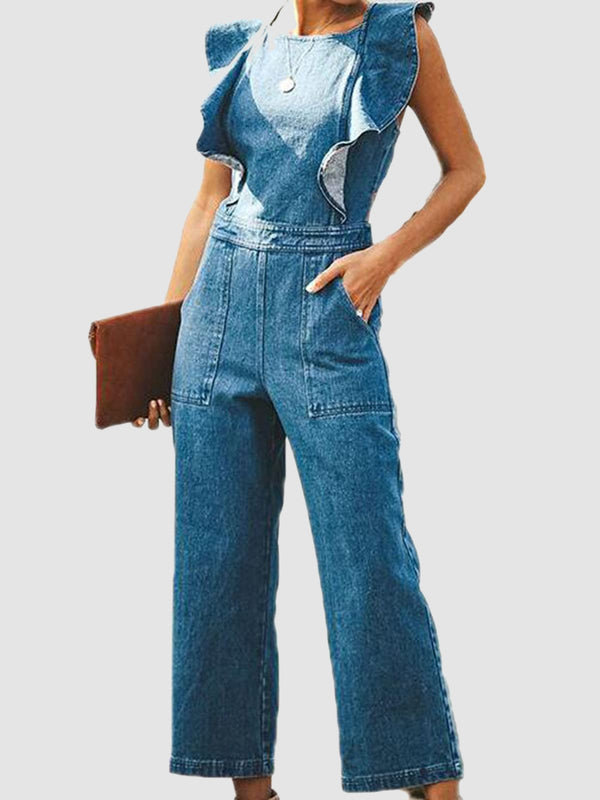 Model wearing the Zelisse Denim Jumpsuit in medium blue, featuring ruffled cap sleeves, a round neckline, and straight-leg silhouette, styled with a brown clutch and pendant necklace.