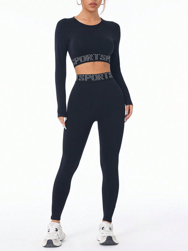 Model wearing ZephyrCore MotifFit Black Active Set, front view showing round-neck top and high-waist leggings with letter print.