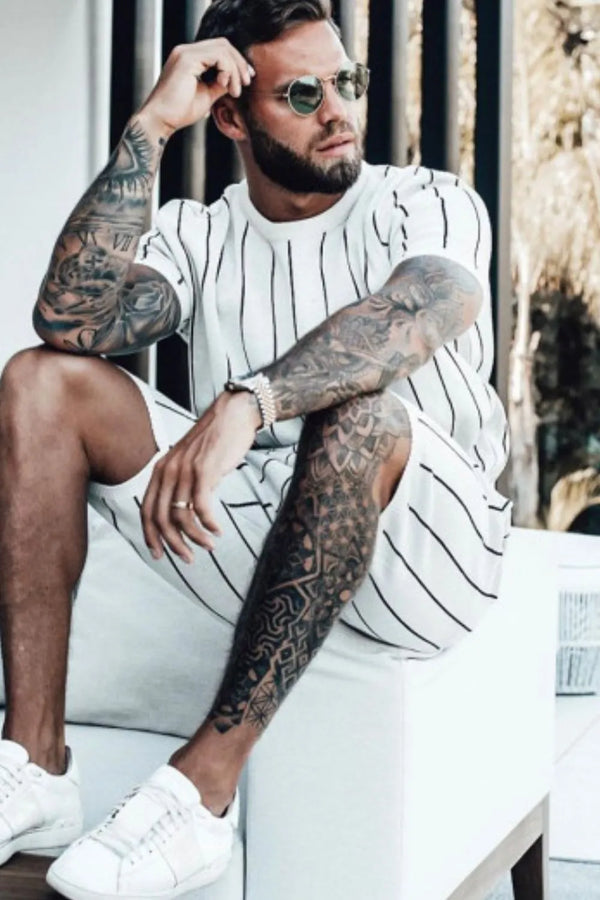 Man lounging on couch wearing white cotton lounge set with black stripes, showcasing relaxed fit.